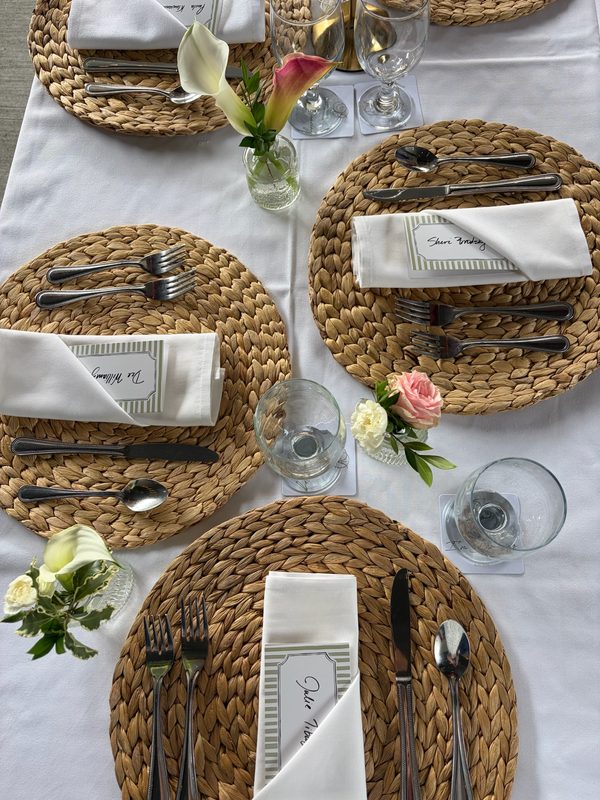 Place settings with woven chargers and mini calla lily vases