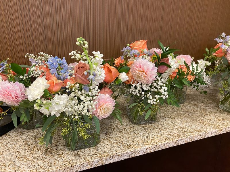 Row of peach and pink arrangements ready for an event
