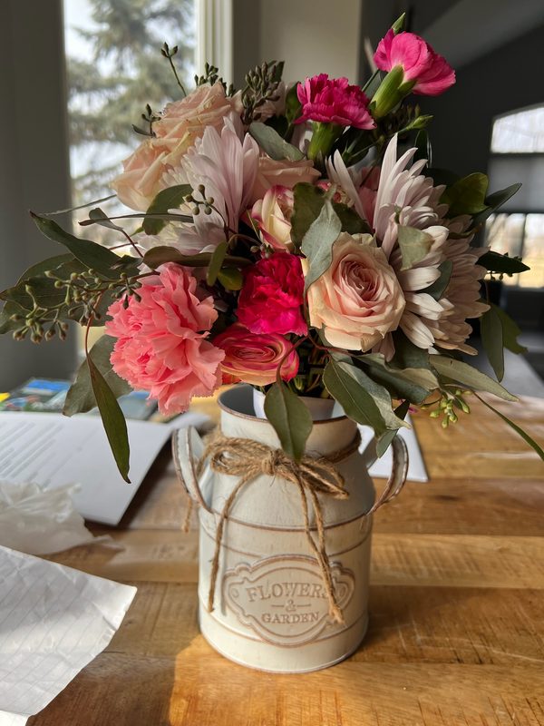 Pink dahlias and roses in a vintage flower tin