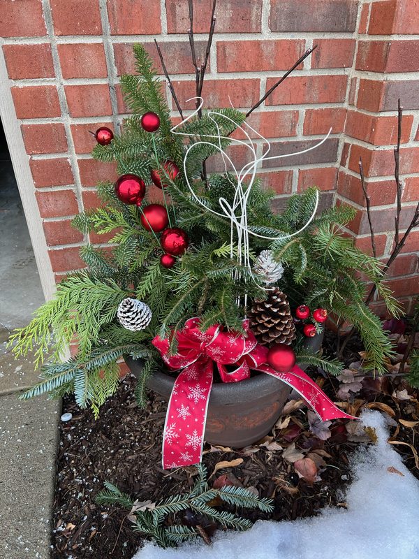 Winter porch planter with evergreens, pinecones and red ornaments