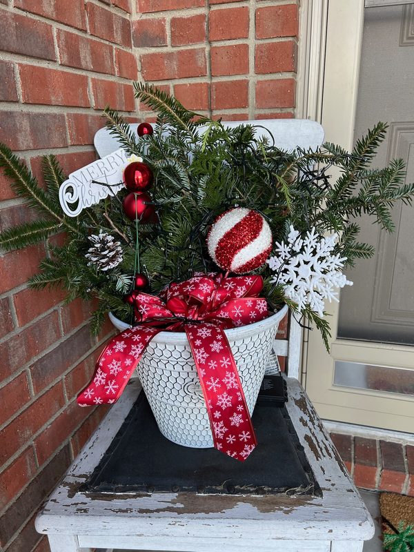 Holiday porch arrangement with evergreens and a red bow