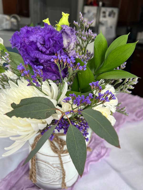 Purple lisianthus and white mums in a rustic jar