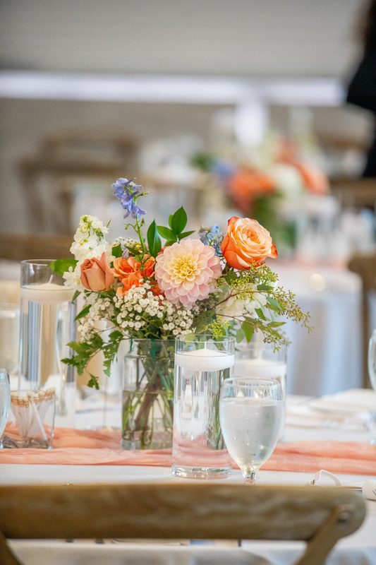 Peach and white centerpiece with candles on a reception table